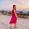 Side view of Strawberry Pink Ikat cotton midi beach dress with oversized bow tie, V-back neckline, and handloom pattern; Abravi sustainable fashion.