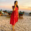Strawberry Pink Ikat cotton mini dress with waist gathers worn at a sunset beach; sleeveless handloom dress with two pockets; Abravi Sustainable fashion.