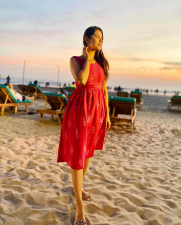 Strawberry Pink Ikat cotton mini dress with waist gathers worn at a sunset beach; sleeveless handloom dress with two pockets; Abravi Sustainable fashion.