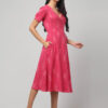 Woman wearing strawberry pink handloom Ikat wrap dress with adjustable waist ties and pockets.