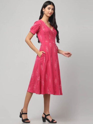 Woman wearing strawberry pink handloom Ikat wrap dress with adjustable waist ties and pockets.