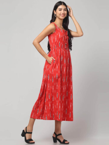 Indian model wearing coral red sleeveless Ikat maxi dress with flare and 2 pockets.