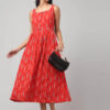 Coral red cotton maxi dress with pockets worn by a Indian woman standing side facing .