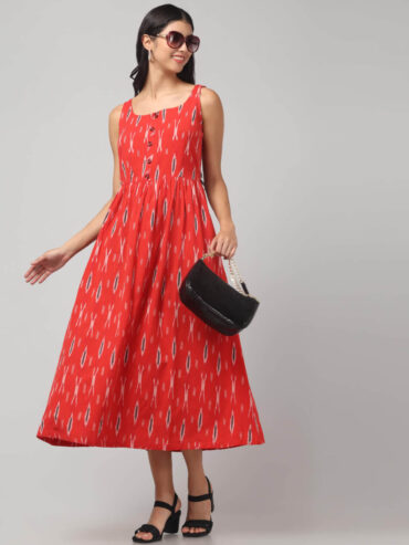 Coral red cotton maxi dress with pockets worn by a Indian woman standing side facing .
