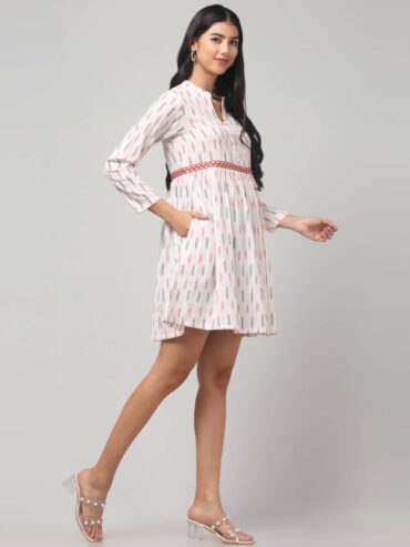Side view of white Ikat handloom cotton dress featuring red zigzag waist embroidery and long sleeves.