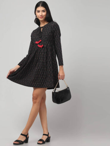 Black Ikat Fit and Flare Frock knee length dress with red tassels and two pockets, worn by a Indian model front-facing.