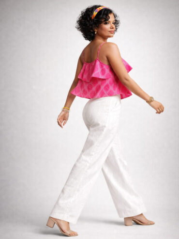 Side view of an Indian female model walking in a pink Ikat Handloom Cotton crop top and white Ikat pants.